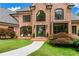 Elegant brick home with manicured lawn, beautiful landscaping, and a welcoming front porch with seating at 6515 Ashbourne Ct, Suwanee, GA 30024