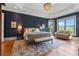 Well-lit main bedroom boasts hardwood floors, tray ceilings, a sitting area, and large windows overlooking the yard at 6515 Ashbourne Ct, Suwanee, GA 30024