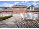 Rear exterior of brick townhouse featuring a driveway leading to a two-car garage and a white picket fence at 8730 Parker Pl, Roswell, GA 30076