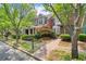 Brick townhome with a cozy front porch, green shutters and lush landscaping, adding to its charm at 8730 Parker Pl, Roswell, GA 30076