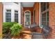 Inviting brick-paved front porch with seating, potted ferns, and view of the brick and bay window exterior at 8730 Parker Pl, Roswell, GA 30076