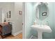 Elegant powder room with pedestal sink, decorative mirror, and stylish fixtures at 8730 Parker Pl, Roswell, GA 30076