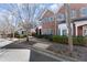 Charming brick townhomes with manicured landscaping line a quiet street with sidewalks and mature trees in a residential neighborhood at 8730 Parker Pl, Roswell, GA 30076