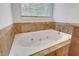 Bright bathroom featuring a soaking tub with stone tiling, jets, and a large window at 200 Renaissance Ne Pkwy # 304, Atlanta, GA 30308