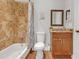 Bathroom featuring stone tile, a tub with shower, and a granite-topped wooden vanity at 200 Renaissance Ne Pkwy # 304, Atlanta, GA 30308