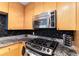 Modern kitchen featuring wood cabinets, granite countertops, black backsplash, and stainless steel appliances at 3338 Peachtree Ne Rd # 3406, Atlanta, GA 30326