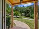 Inviting covered front porch view, framed by wooden beams, with a glimpse of the serene, tree-lined street and the house in the distance at 3912 Edenton Ne Ct, Brookhaven, GA 30319