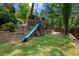Backyard playset with slide, climbing structure, swing set, and retaining wall at 3912 Edenton Ne Ct, Brookhaven, GA 30319