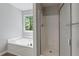 Bathroom featuring shower/tub combo and corner tub under window for natural light at 3935 Hamilton View Way, Dacula, GA 30019