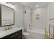 Modern bathroom featuring a black framed mirror, white tiled walls and a black vanity with gold accents at 6835 Sunny Brook Ln, Atlanta, GA 30328