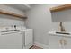 Bright laundry room with quartz countertop, wooden accent shelf and stainless steel washer and dryer at 6835 Sunny Brook Ln, Atlanta, GA 30328