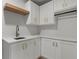 Well-organized laundry room with white cabinets, quartz countertop and wooden accent shelf above sink at 6835 Sunny Brook Ln, Atlanta, GA 30328