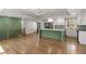 Open-concept living space with hardwood floors, a green kitchen island, and elegant staircase at 6835 Sunny Brook Ln, Atlanta, GA 30328