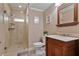 Bathroom featuring stone shower with glass door, a wooden vanity, framed mirror, and tiled floors at 3920 Ineal Dr, Cumming, GA 30028