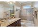 Bright bathroom with granite counters, decorative mirror and a shower-tub combination with glass doors at 3920 Ineal Dr, Cumming, GA 30028