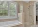 Bright bathroom featuring a combination tub and shower with neutral tile surround at 4810 Duncans Lake Dr, Buford, GA 30519