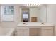 Bright bathroom featuring dual sinks, white cabinets, large mirror, and a soaking tub at 512 Antler Ln, Suwanee, GA 30024