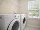 A laundry room featuring a washer, dryer, window, and wire shelving at 5244 Carrington Park Dr, Powder Springs, GA 30127