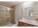 Bright bathroom featuring a tiled shower with glass doors and a vanity with a decorative mirror at 12084 Cotton Aly, Alpharetta, GA 30009