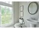Bright powder room featuring a pedestal sink, a large window, and tasteful botanical prints at 12084 Cotton Aly, Alpharetta, GA 30009
