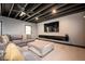 Finished basement with an exposed ceiling, a modern sofa, and a wall-mounted entertainment center at 2927 Dolostone Way, Dacula, GA 30019