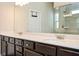 Bathroom featuring a double vanity with dark cabinets and a view of the tiled walk-in shower at 2927 Dolostone Way, Dacula, GA 30019