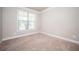 Empty bedroom with neutral carpet, a window and base molding at 2927 Dolostone Way, Dacula, GA 30019