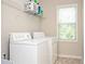 A laundry room with a set of white washer and dryer units and a window for natural light at 2927 Dolostone Way, Dacula, GA 30019