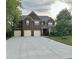 Traditional brick home with three-car garage, manicured lawn, and mature landscaping at 556 Georgia Cir, Loganville, GA 30052