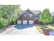 A grand brick home featuring a three-car garage, lush front lawn, and mature trees at 556 Georgia Cir, Loganville, GA 30052