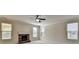 Cozy living room with fireplace, three windows, and a ceiling fan for comfortable living at 556 Georgia Cir, Loganville, GA 30052