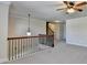 A neutral loft space with decorative lighting, carpet flooring, and dark iron railing at 556 Georgia Cir, Loganville, GA 30052
