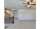 Open loft features neutral carpet and walls with a ceiling fan and adjacent staircase at 556 Georgia Cir, Loganville, GA 30052