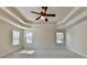Bright main bedroom featuring a ceiling fan, coffered ceilings, and three windows with natural light at 556 Georgia Cir, Loganville, GA 30052