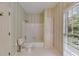 Charming bathroom features tub/shower, toilet, storage cabinet and window overlooking lush greenery at 9395 Clublands Dr, Alpharetta, GA 30022