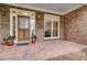 Welcoming front porch featuring a stylish wooden door, brick flooring, and decorative flower pots at 9395 Clublands Dr, Alpharetta, GA 30022