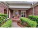 Charming brick home entrance with a wooden door, brick porch, and lush green landscaping at 9395 Clublands Dr, Alpharetta, GA 30022