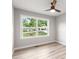 Bright bedroom featuring a ceiling fan, grey walls, light-colored wood floors and a large window showing the yard at 2026 Rebecca Ln, Decatur, GA 30032