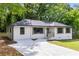Charming home with a new driveway, white brick, dark-trimmed windows, and lush surrounding trees at 2026 Rebecca Ln, Decatur, GA 30032