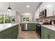 Updated kitchen showcasing stainless appliances, white upper cabinets and lower green cabinets, open to natural light and outdoors at 2026 Rebecca Ln, Decatur, GA 30032