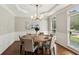 Bright dining room with a wooden table and six chairs, featuring wainscoting, tray ceilings, and large windows at 4140 Lansfaire Ter, Suwanee, GA 30024