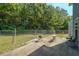 A fenced backyard featuring a small patio with grill and seating, adjacent to a grassy area and trees at 6220 Polar Fox Ct, Riverdale, GA 30296
