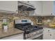 Close-up of the kitchen features including a stainless steel stove, stone countertops and mosaic backsplash at 8007 Northcrest Dr, Jonesboro, GA 30238