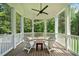 Screened in porch features white Adirondack chairs, ceiling fan, and wooded backyard at 1064 Highway 20 E, Mcdonough, GA 30252