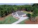 Aerial view showcasing a white farmhouse-style home, lush greenery, and a spacious two-car garage at 140 Paislee Park (Lot #5 Paislee Park) Dr, Fayetteville, GA 30215