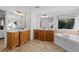 Bathroom features dual vanities, soaking tub, framed mirrors, and a window view at 1481 Wild Rye Ln, Grayson, GA 30017