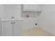 Well-lit laundry room with white cabinetry, a sink, and tile flooring at 1481 Wild Rye Ln, Grayson, GA 30017
