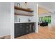 Stylish bar area featuring dark cabinets, floating shelves, and a beverage cooler, perfect for entertaining at 3267 Sewell Mill Rd, Marietta, GA 30062