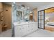Elegant bathroom with dual sinks, marble accent wall, wood-look floors, and a door leading to bedroom at 3267 Sewell Mill Rd, Marietta, GA 30062