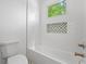 White tiled bathroom with a tub, toilet, and a decorative inset shelf above the tub at 3267 Sewell Mill Rd, Marietta, GA 30062
